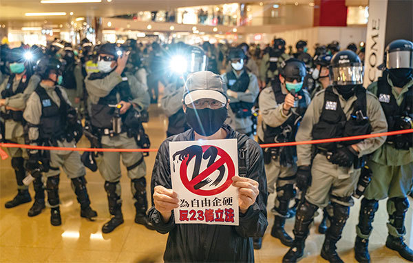 2020年4月26日太古城商場發起千人大合唱「願榮光歸香港」，有市民在警察警戒線前手持反對23條立法的標語。（Anthony Kwan/Getty Images）