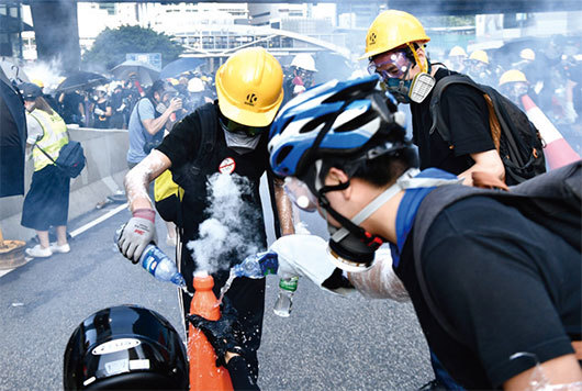 8月5日17時50分，警方在金鐘夏慤道一再施放催淚彈。示威者衝上去熄滅催淚彈。（Getty Images）