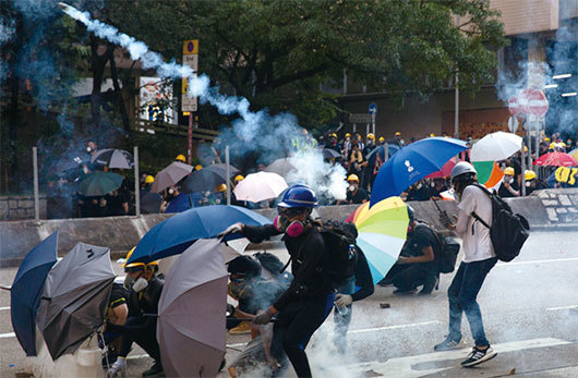 8月5日18時25分，黃大仙處警方持續施放多枚催淚彈。示威者用雨傘遮擋。（Getty Images）