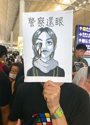 8月12日起，港人將長期展開「百萬人塞爆機場」集會。圖為民眾持「警察還眼」的圖畫抗議警察暴力。（王文君／大紀元）