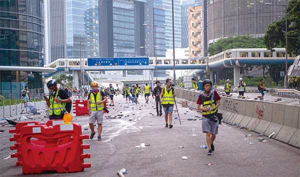 2019年8月24日，香港觀塘偉業街，警察發射催淚彈清場後現場凌亂。穿黃馬甲的都是記者。（余鋼／大紀元）