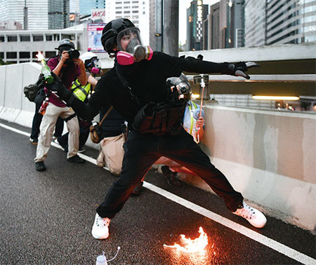 8月31日一名黑衣男子丟擲汽油彈。身上卻佩戴槍枝，且頭盔同廣東特警的頗為相似。（AFP）