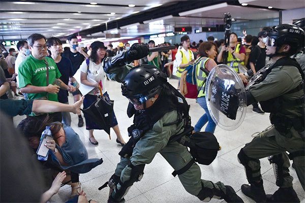 9月8日，一名警察揮舞警棍毆打一名年輕女生。（Getty Images）