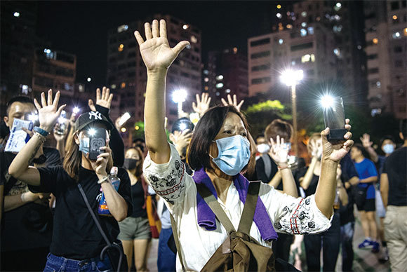 香港政府宣布實行「禁蒙面法」後，10月5日，香港民眾蒙面港島遊行，民眾伸出五個手指表達「五大訴求 缺一不可」。（Getty Images）