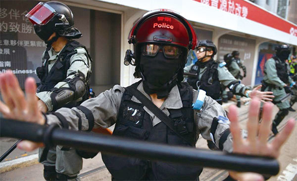 一群香港警察10月5日在港島中區追捕一對戴著口罩上街抗議的夫婦後，一名香港警察試圖封鎖該地區，阻擋媒體記者上前採訪。（AFP）