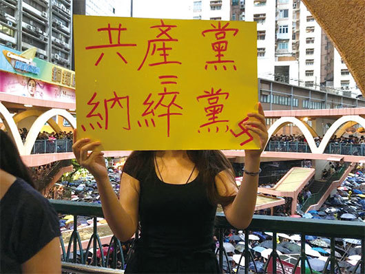 8月18日和理非組織的維園集會上，有人手持「共產黨＝納粹黨」標語。一名九零後女子上台說，「香港的運動打開共產黨滅亡的大門」。（葉依帆／大紀元）