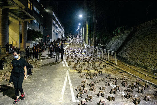抗議者在香港中文大學校園內的道路上堆積磚塊作為路障。（AFP）