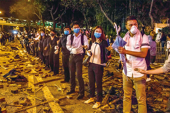 18日晚，大批聲援被困理大生的市民，在校園一帶主要馬路與防暴警對峙，並組成人鏈運送物資。（AFP）