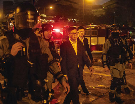 香港新上任的警務處處長鄧炳強（圖中穿西裝者）12月上旬到北京拜訪兩天。圖為他於11月19日在香港理工大學校園。（Getty Images）