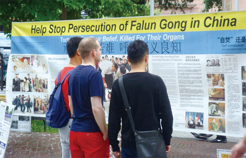 德國部分法輪功學員2017年7月22日在法蘭克福市中心、中國遊客經常光顧的商業街舉辦資訊日活動。行人在觀看法輪功真相介紹。（謝文美／大紀元）