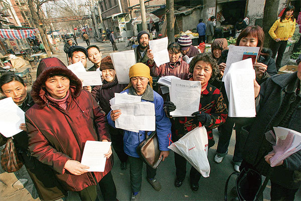 2005年中共兩會前夕，在北京南面住了上百人士的上訪村，上訪人士向媒體展示訴狀。（AFP）