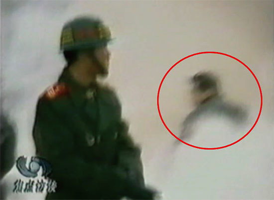 CCTV「自焚」節目慢動作分析-4：一名身穿大衣的男子正好站在出手打擊的方位，仍然保持著一秒鐘前用力打擊的姿勢。