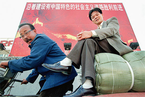 改革開放之初，紅色中國大力宣揚「中國特色社會主義」，妄圖把自己的模式擴散出去。圖為1997年10月16日北京平板自行車拖著一個商人。（Robyn Beck / AFP）