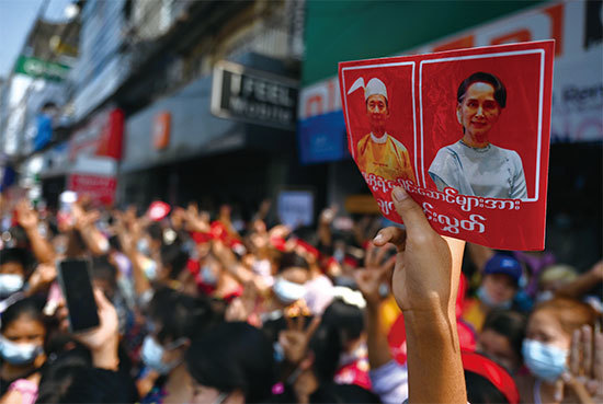 民眾抗議軍方政變，一民眾手持温敏及昂山素季肖像。（Ye Aung Thu / AFP）