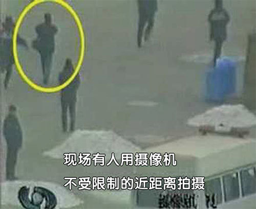 「自焚」錄像中可看到一個背攝影包的男子正在廣場軍警中從容地跟進拍攝。他為何可以自由拍攝？（明慧網）
