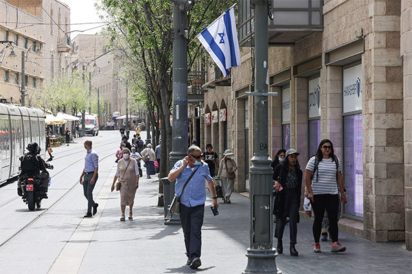 2021年4月18日，在以色列當局宣布戶外不需戴口罩後，人們在耶路撒冷的一條街道上行走。（Menahem Kahana / AFP）