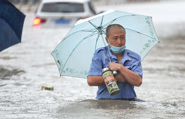今年中國北方發大水，水勢凶猛，造成很大災害。圖為2021年7月20日河南鄭州市下大雨後，一名男子沿著街道涉水穿過洪水。（STR/AFP）