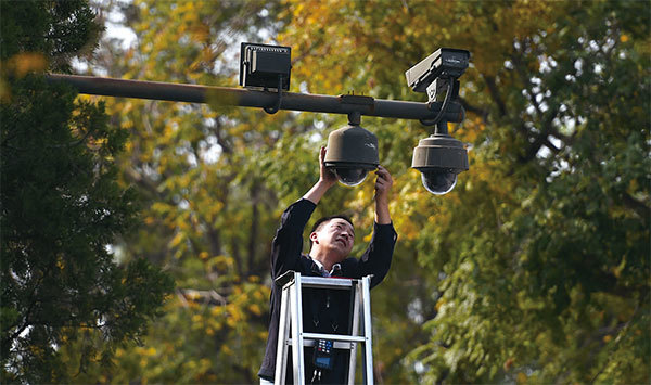 全球安裝監控攝像頭的數量在2021年底將超過10億個，中國占總數的一半以上。圖為2014年9月30日，一名工人在天安門廣場周圍調整監控攝像頭。（Greg Baker / AFP）