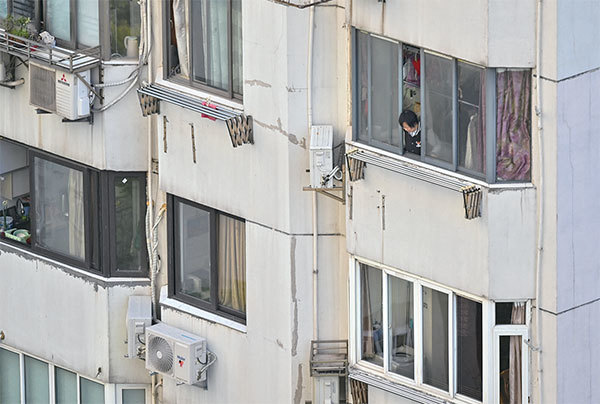 日前，《衛報》刊出一位上海居民的封城日記，記錄了計畫供應、以物換物、焦慮以及飢餓的經歷。圖為4月9日，上海封城期間，靜安區一名民眾由公寓裡向外張望。（HECTOR RETAMAL / AFP）