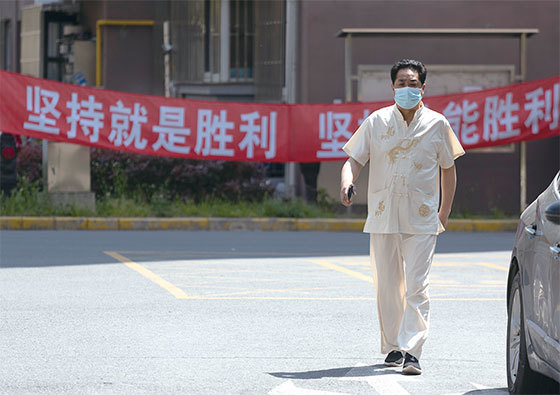 三退民眾表示，「共匪如同腫瘤一樣通過吸食人民的血肉來維持自己的統治！」圖為4月12日上海一名男子走在掛有中共宣傳標語的住宅區。（Getty Images）