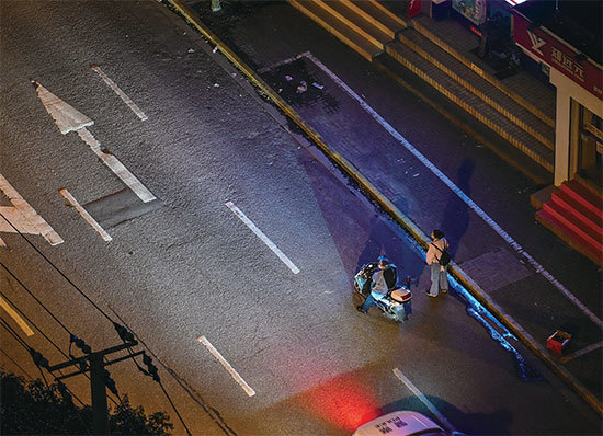 2022年4月18日，上海靜安區封鎖期間，一名穿著防護服的警察及一名居民在空蕩的街道旁。（Hector Retamal / AFP）   