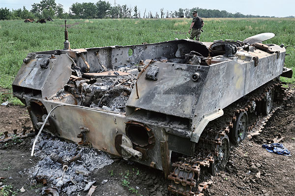 圖為2022年6月12日，一名烏克蘭軍人在鄰近烏克蘭南部城市Mykolaiv，走過一輛被毀壞的俄羅斯軍用車輛。（Genya Savilov / AFP）