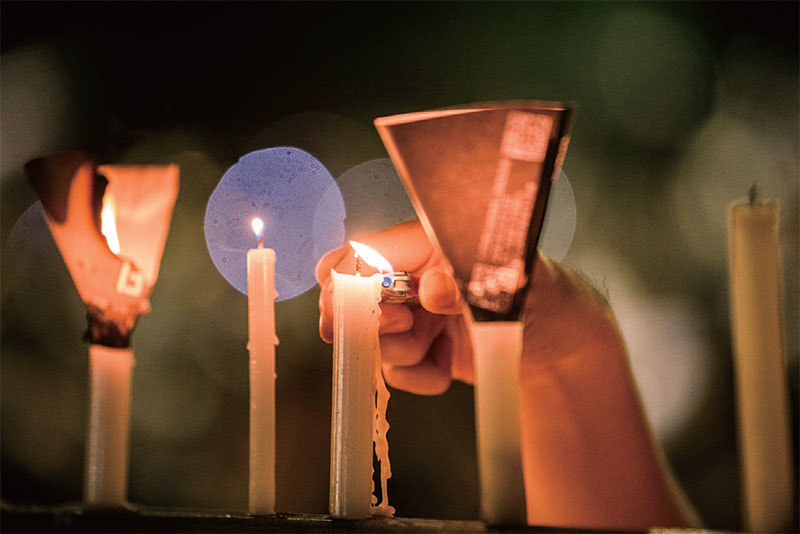 父親教書育人50多年，「六四」時他保護學生，被稱為學生的天。圖為2020年6月4日，一名男子在香港維園參加六四燭光夜悼時點燃蠟燭。（Anthony Wallace / AFP）