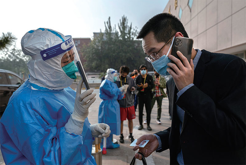 拖累中國經濟增長的主要原因首先是抗疫清零。圖為2022年10月21日參加中共二十大的記者、工作人員和官員在一家閉環酒店外排隊等待核酸檢測。（Kevin Frayer / Getty Images）