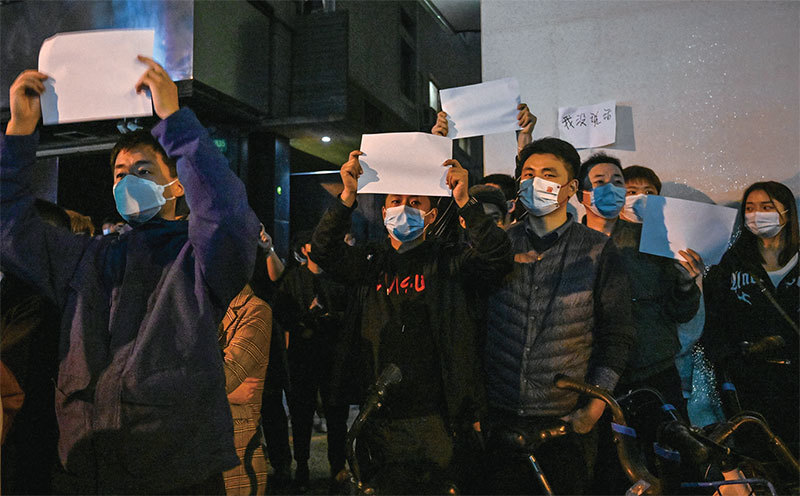 2022年11月26日，上海烏魯木齊中路，民眾手舉白紙高喊「新疆解封！」（Hector Retamal / AFP）