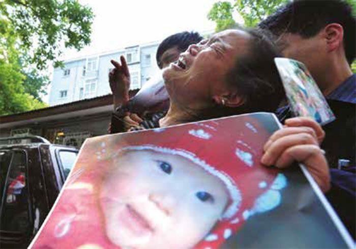 大陸社會上假冒偽劣現象泛濫成災，誠信危機深重。圖為2009年5月8日一婦人手捧孫女的遺像在北京悲痛控訴三鹿奶粉的毒害。（Getty Images）