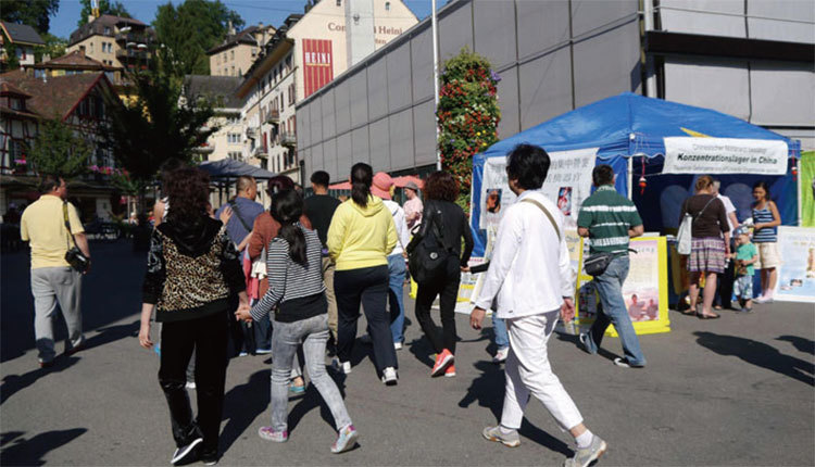 在瑞士盧塞恩景點，中國遊客路過法輪功信息攤位。（明慧網）