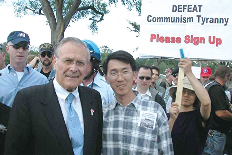 2005年5月29日下午美國國防部長拉姆斯菲爾德（Rumsfeld）聲援並在退黨徵簽中心前和三退義工合影。（大紀元）