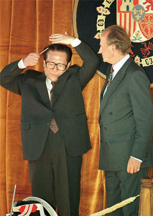 江澤民在外交場合喜好吹拉彈唱，梳頭打扮，成為海外政界的笑料。圖為西班牙卡洛斯國王錯愕地看著江澤民梳頭。（AFP）