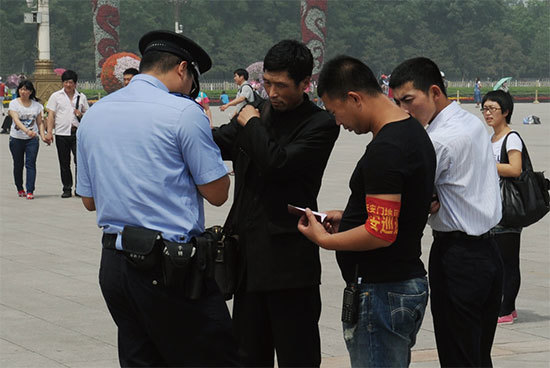 2012年中共「六四」屠城23周年之際，北京警察在天安門廣場檢查一名男子身分證並逮捕了他。（Getty Images）