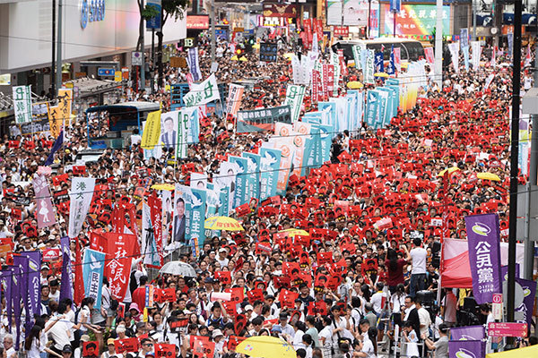 9日那天，總人口700萬人的香港，有100多萬市民都走出來參加遊行。許多抗議者穿著白色T恤，揮舞著反送中的紅色標誌，呼籲北京支持的特首林鄭月娥下臺。（宋碧龍／大紀元）