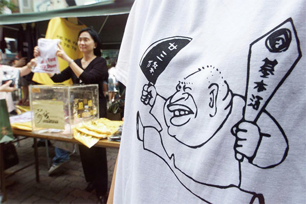 香港特首董建華（T恤上的漫畫人像）因為在江澤民授意下強推《基本法》第23條立法，引發2003年7月1日50萬港人大遊行，隨後被迫提前辭職。（Getty Images）