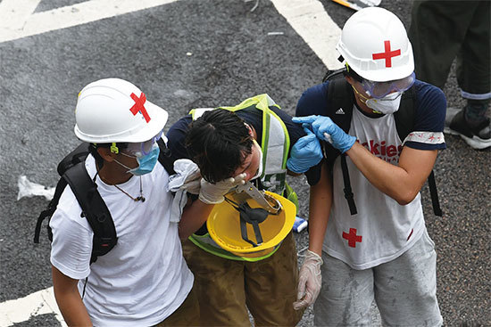 6月12日，警方發射催淚彈驅趕民眾。圖為一位抗議者扔回催淚彈。（AFP）