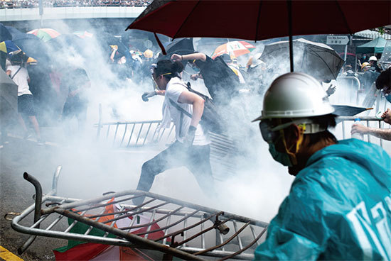 6月12日，香港上萬人將立法會周邊圍得水洩不通。圖為抗議民眾逃離警方發射的催淚彈。（AFP）