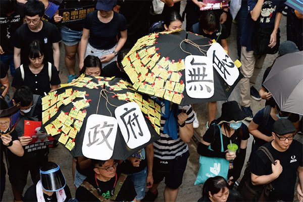圖2：2019年7月21日，香港，民陣發起的反送中遊行隊伍中，有市民舉起掛上政府無恥紙牌和貼滿便利貼的雨傘。（宋碧龍／大紀元）